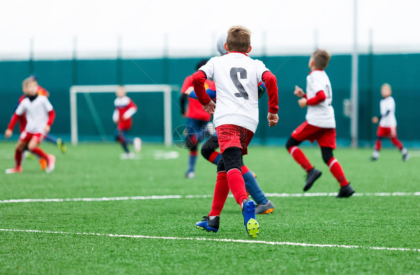 足球队身着红蓝白制服的男孩在绿地上踢足球男孩运球运球技巧团队游戏训练积极生活方式爱好图片