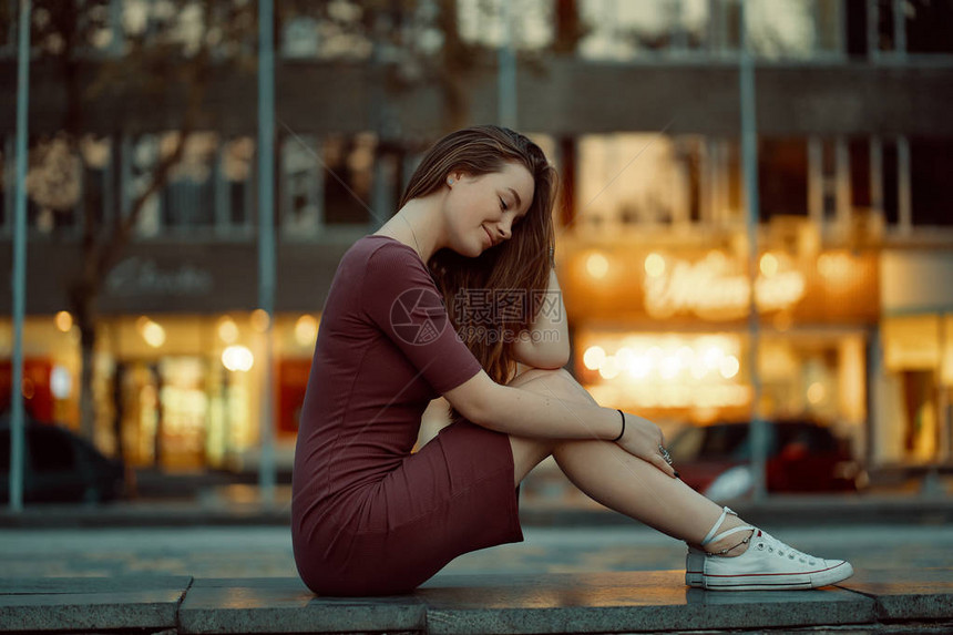 具有童话般面孔特征的漂亮年轻女子的侧视图在背景中享受城市景观美丽的城市女孩肖像穿着连衣裙图片