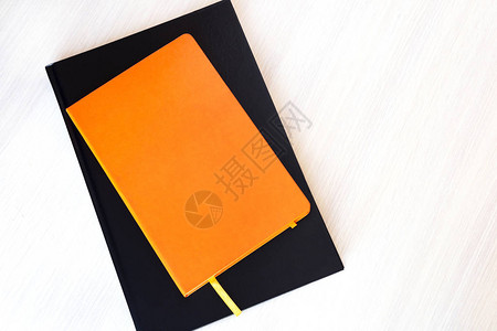 将橙色和黑橘色书籍或笔记本以及桌上的复制图片