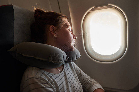 一个在飞机上睡觉的年轻女孩乘客睡在飞机上愉快高清图片素材