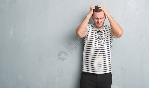 灰色墙壁上的年轻天主教男子头痛绝望图片