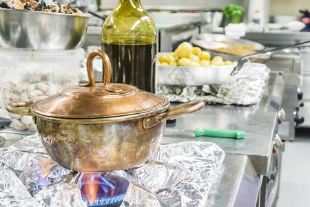 餐厅燃气灶上带食物的老式铜锅图片