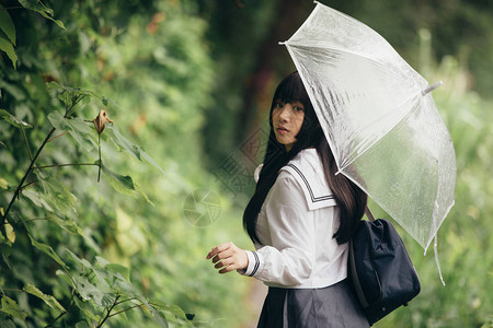 下雨时在自然行走道上带着雨伞走路的亚图片