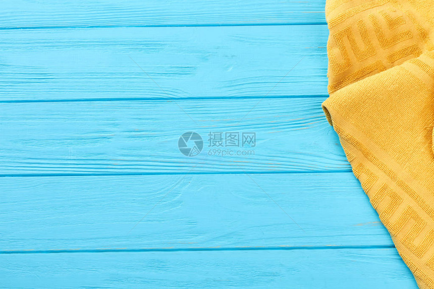 蓝色木制背景上的黄色毛巾蓝色木板上的彩色毛巾和复制空图片