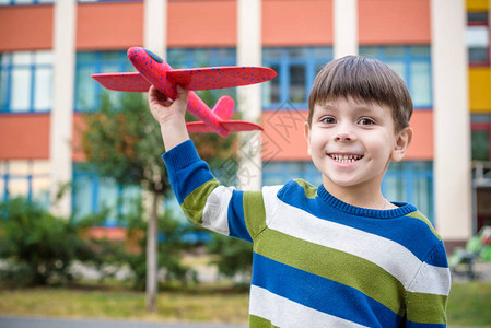 快乐的孩子在漂亮的建筑背景下玩具飞机男孩在或幼儿园领域扔泡沫飞机最图片