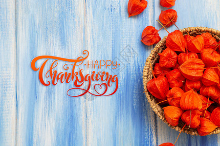 感恩节信件秋天的背景蓝色木质背景上的明亮橙色酸浆果祝贺秋季图片