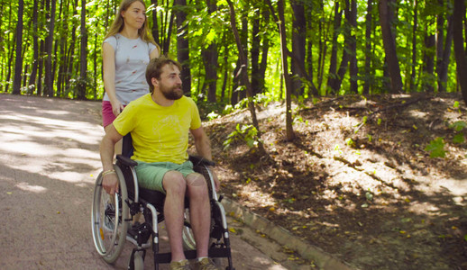 年轻的残疾男子坐在轮椅上与妻图片