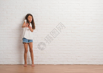 年轻的西班牙小孩在白砖墙上挥舞着令人厌恶的表情不高兴和恐惧地脸朝反感图片