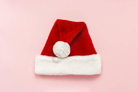 圣诞老人的帽子在温柔的粉红背景上构思和圣诞快乐平坦的躺图片