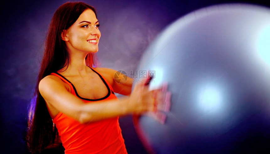 健身女孩瑜伽在带球的健身房里锻炼健身球的女人在运动室的多色光线中工作全长肖像在配置文件与镜头光晕在夏天创图片