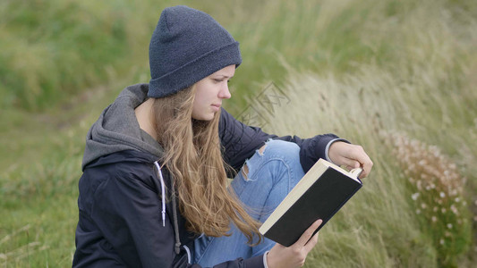 女孩坐在草丛里看书图片
