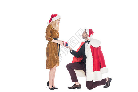 穿着圣诞老人服装的男人向戴着圣诞老人帽子的女朋友送礼物图片