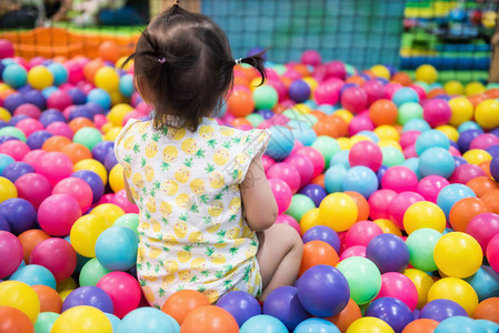 罕见的小女孩在彩色球的坑中玩耍的镜头孩子在室内游乐场玩耍球图片