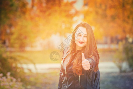一位年轻女生的秋天户外肖像举起拇指就像手势背景图片