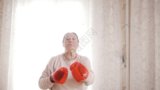 一位戴着红手套拳击的老妇人肖像图片