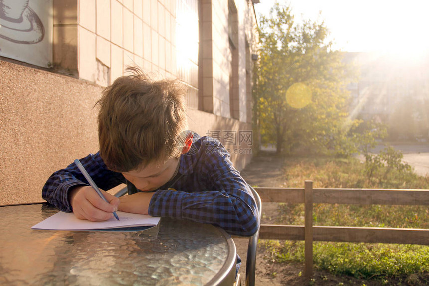 男孩在户外做家庭作业男孩用纸画或写信图片