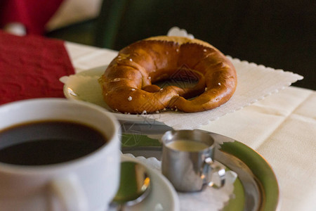 加上奶油和一杯黑咖啡红桌布的德国煎饼加背景图片