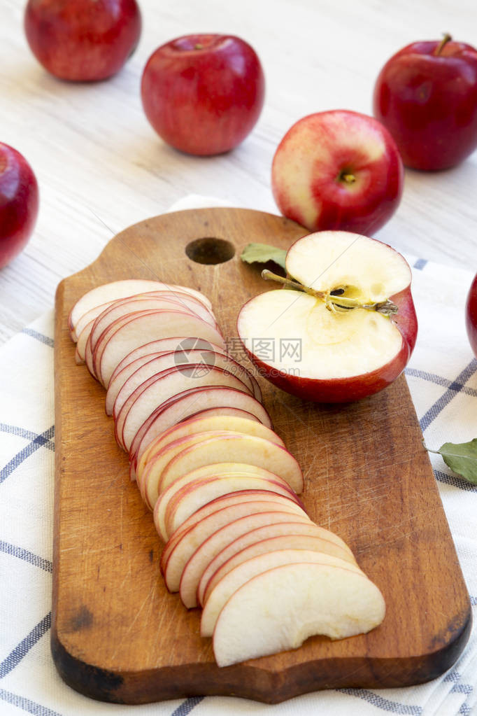 铁制木板上的红有机苹果切片在白色木制背景图片