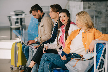 年轻人坐在一起等待在机场候机站的背景图片