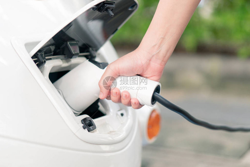 亚洲妇女带来电池充电器与电动汽车连接将电动汽车放入车内清洁能源不会污染空气节能理图片