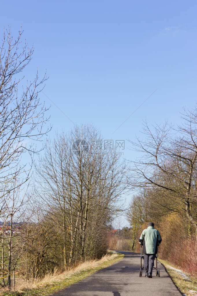 高级男子在自行车上驾驶滚动车在南德的蓝天和阳图片