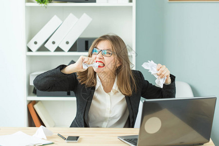 人们商业和情绪概念年轻女用沮丧的面部表情撕毁文件图片