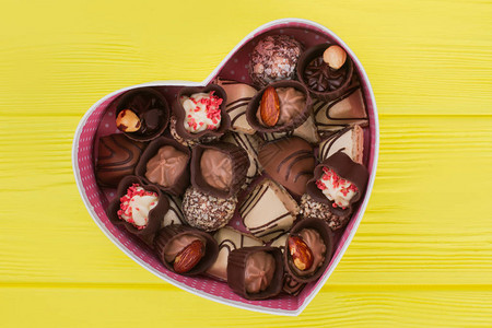 巧克力类装在心形礼品盒里黄木本底的美味糖果情人节的概念图片