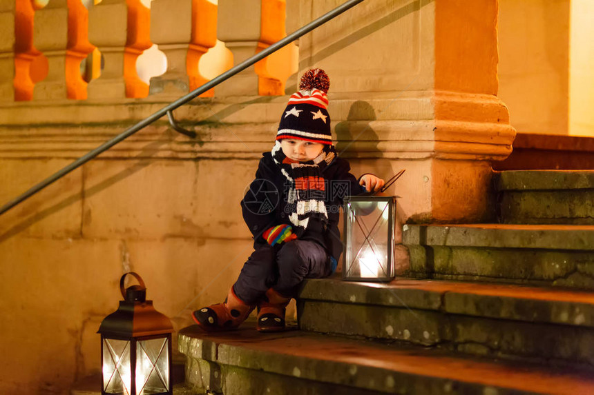 可爱的小男孩在教堂附近的楼梯上带着一盏德国圣诞市场上快乐的孩子孩子在寒冷的图片