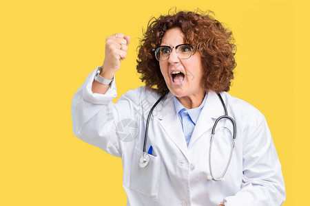 中年高级医生女人在孤立的背景下愤怒和疯狂地举起拳头沮丧和愤怒图片