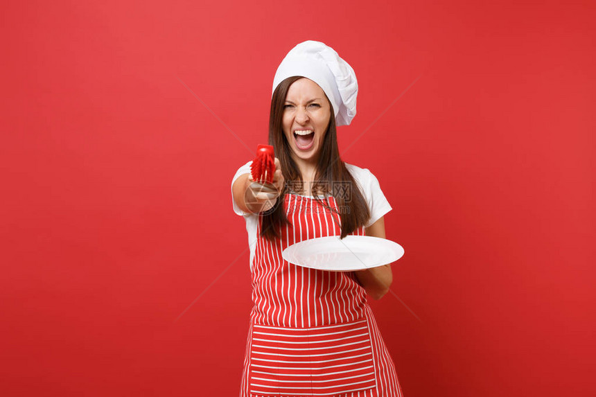 家庭主妇女厨师或面包师穿着条纹围裙白色t恤无边帽厨师帽隔离在红墙背景上女人拿着白盘子用刷子洗碗模拟图片