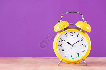 闹钟旧复古时钟与铃木桌上和紫色背景时钟为黄色文本和设计的空间图片
