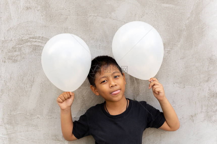 小亚洲小男孩拿着白气球在灰图片