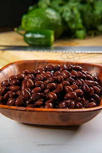 大理石柜台上的辣椒配料木碗黑龟豆背景图片