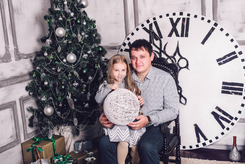 家人聚集在圣诞树附近中的时钟显示距离午夜还有五分钟平安夜新年假期和乐趣图片