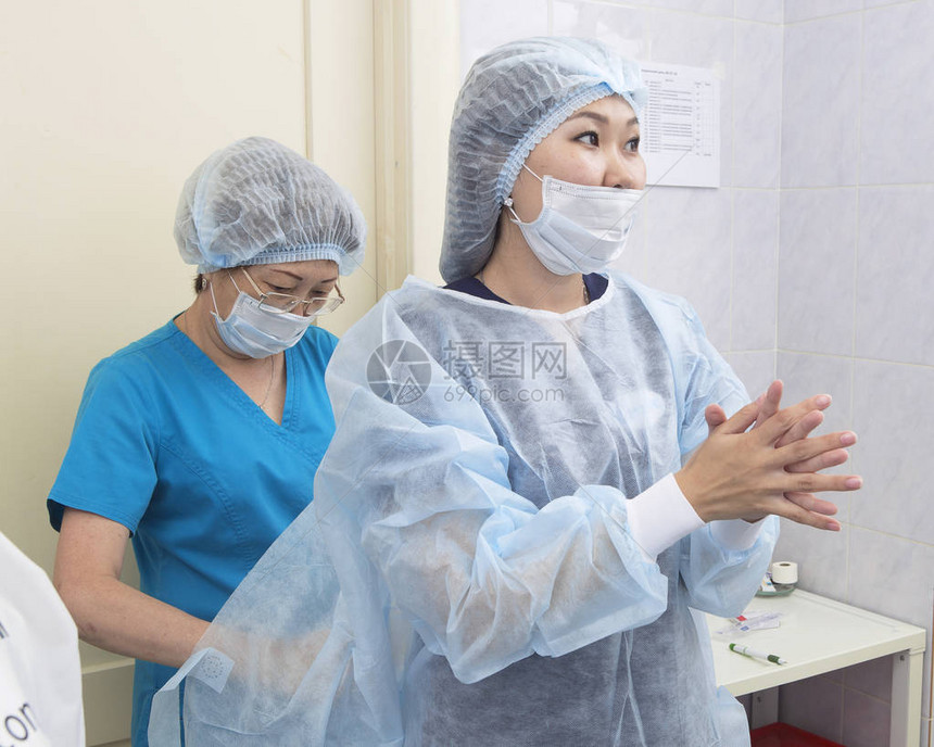一名护士帮助一名女外科医生一名眼科医生穿上防图片