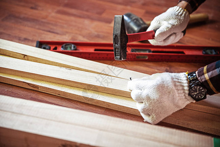 在敲钉子的同时用锤子建造DIY专业木匠在房子里使用木材和建筑图片