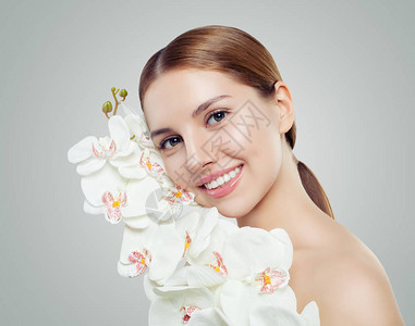 年轻的微笑女人与健康的皮肤和白色的兰花护肤水疗美容美容和图片
