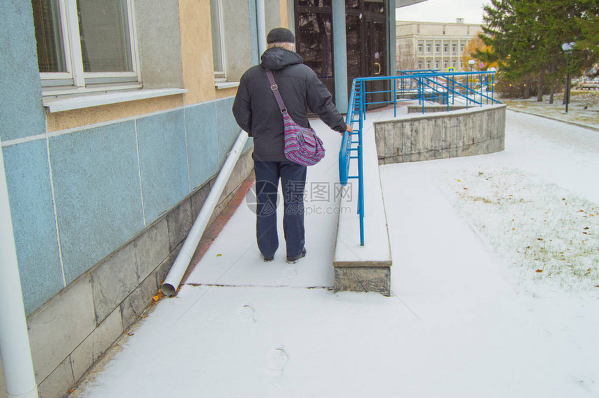 一位白发苍的老病人艰难地爬上积雪覆盖的残疾人坡道图片