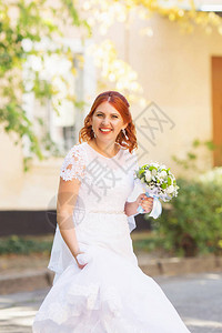 美丽的红发新娘与室外的花束快乐的新娘在户外跳跃和玩乐美丽的新娘在婚图片