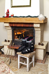 在壁炉前晒鞋两双滑雪靴站在明亮的房间里燃烧的壁图片