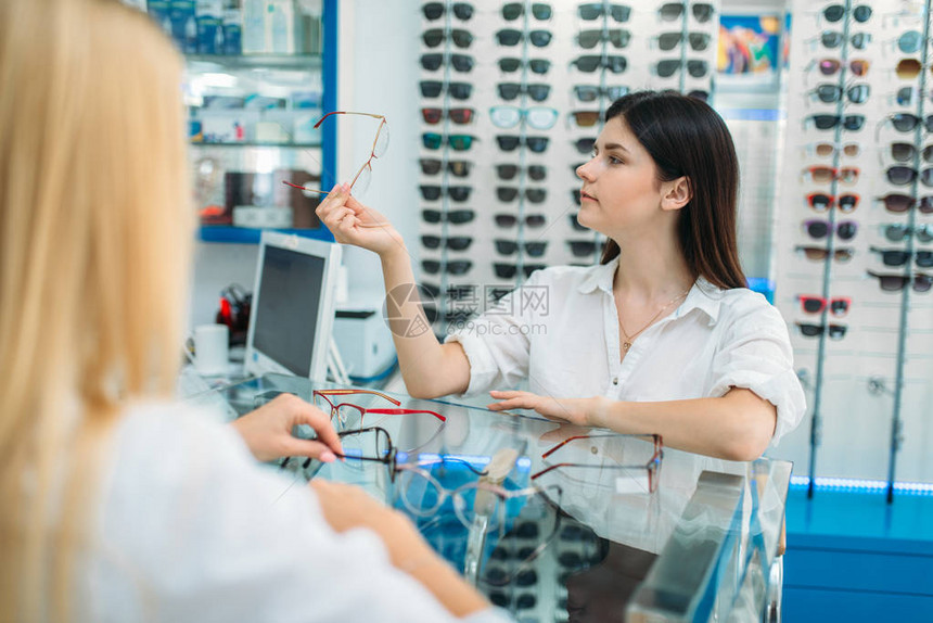 女光学和消费者在光学商店中选择眼镜框图片
