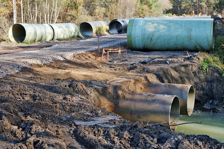 大型下水道管位于秋天森林建筑工地的沙土和上图片