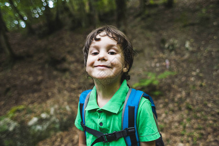 一个微笑的男孩的画像一个背着书包的孩子在公园里散步孩子穿过森林图片