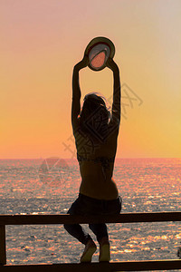 一位女孩在空中举起手来带着海洋海背图片