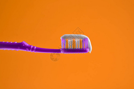 紫色牙刷上的牙膏在橙色图片