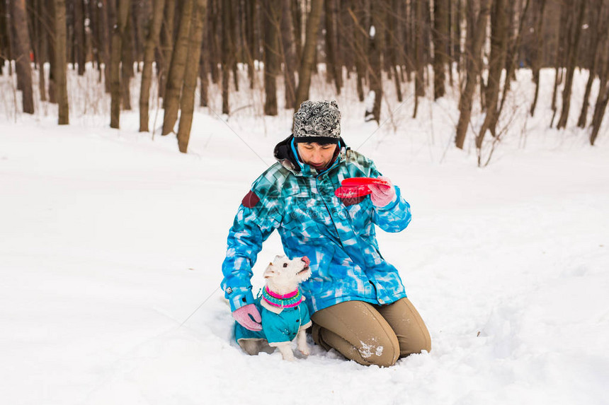 宠物主人和冬季概念中年妇女在雪地公园玩图片