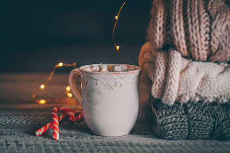 堆叠着舒适的编织毛衣和咖啡或热巧克力图片