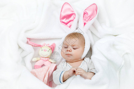 可爱的可爱新生女婴穿着复活节兔子服装和耳朵可爱的孩子在玩毛绒兔子玩图片