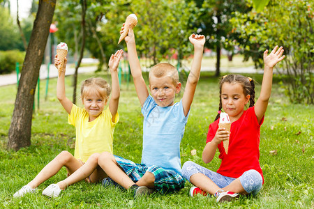 小孩坐在绿草上吃冰淇淋图片