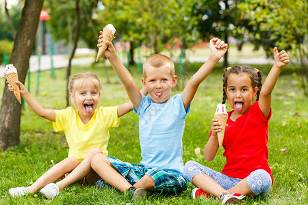 小孩坐在绿草上吃冰淇淋图片